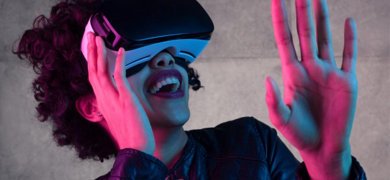 A woman laughs while wearing a virtual reality headset