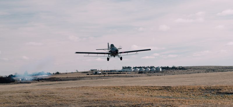 a crop duster airplane flying low over a field