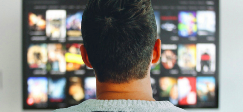 Man in front of a TV choosing from streaming television options.