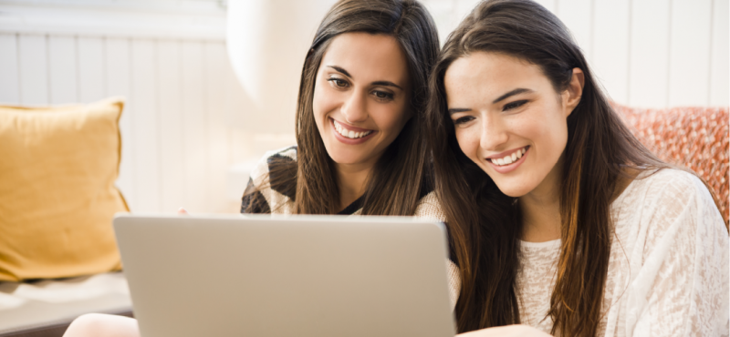Two young women using a laptop at home.