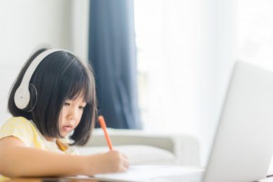 A young girl learning remotely on a laptop