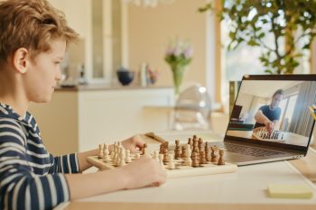 a young boy playing chess with an adult on the internet