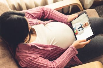 a pregnant woman has a telemedicine appointment with her doctor