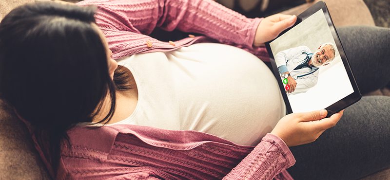 a pregnant woman has a telemedicine appointment with her doctor