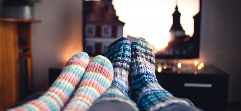 two people wearing thick socks watch a tv show together